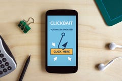 Concetto di Clickbait sullo schermo dello Smart Phone sullo scrittorio di legno Fotografia Stock Libera da Diritti Concetto di Clickbait sullo schermo dello Smart Phone sullo scrittorio di legno Fotografia Stock Libera da Diritti