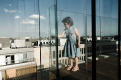 Concetto di infanzia Piccolo ragazza prescolare sveglia sul balcone di vetro fotografia stock Concetto di infanzia Piccolo ragazza prescolare sveglia sul balcone di vetro fotografia stock