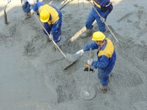 Concrete mix leveling. Construction workers spreading freshly poured concrete mix at the building site Concrete mix leveling. Construction workers spreading freshly poured concrete mix at the building site