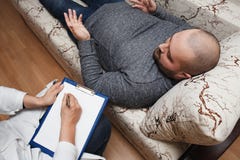 Conduzione dello psicologo Giovane durante la visita dello psicoterapeuta, parlante dei suoi problemi con le emozioni, salute men immagine stock Conduzione dello psicologo Giovane durante la visita dello psicoterapeuta, parlante dei suoi problemi con le emozioni, salute men immagine stock