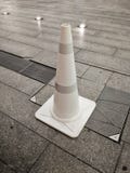 Cone plástico branco do tráfego em um assoalho de pedra do bloco ilustração royalty free Cone plástico branco do tráfego em um assoalho de pedra do bloco ilustração royalty free