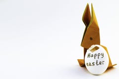 Conejo de la papiroflexia del papel de color naranja Conejito de pascua y blanco con una cáscara de huevo tajada con una inscripc fotos de archivo libres de regalías Conejo de la papiroflexia del papel de color naranja Conejito de pascua y blanco con una cáscara de huevo tajada con una inscripc fotos de archivo libres de regalías