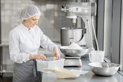 Confettiere della donna che lavora alla fabbricazione del forno immagine stock Confettiere della donna che lavora alla fabbricazione del forno immagine stock