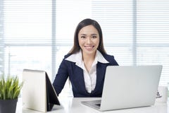 Confident asian businesswoman sitting by desk with laptop in office stock image Confident asian businesswoman sitting by desk with laptop in office stock image