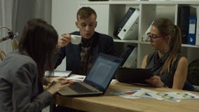 Business partners discussing charts at workplace. Confident businesswoman in eyglasses with digital tablet discussing financial charts and graphs with male Business partners discussing charts at workplace. Confident businesswoman in eyglasses with digital tablet discussing financial charts and graphs with male