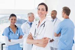 Confident female doctor smiling at camera with her team behind stock photography Confident female doctor smiling at camera with her team behind stock photography