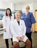 Confident Male Doctor Sitting By Team In Clinic royalty free stock images Confident Male Doctor Sitting By Team In Clinic royalty free stock images