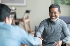 Confident mature Asian man sitting, smiling and shaking hand with partnership after making profitable agreement. stock photos Confident mature Asian man sitting, smiling and shaking hand with partnership after making profitable agreement. stock photos