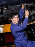 Confident Mechanic Repairing Underneath Car royalty free stock photography Confident Mechanic Repairing Underneath Car royalty free stock photography