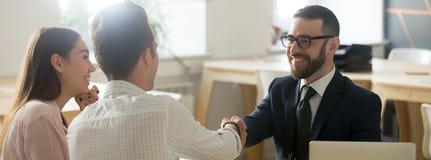 Confident realtor greeting clients young married couple in office stock photo Confident realtor greeting clients young married couple in office stock photo