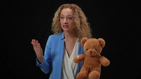 Confident woman holding teddy bear talking looking around persuading in kidnapping problem importance. Portrait of
