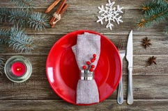 Configuration de table de Noël Plat rouge, serviette, fourchette, couteau, branche d'un arbre sur une table en bois photo libre de droits Configuration de table de Noël Plat rouge, serviette, fourchette, couteau, branche d'un arbre sur une table en bois photo libre de droits