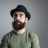 Confused bearded man wearing black hat looking away. Headshot close up portrait over gray studio background with vignette Stock Photography Confused bearded man wearing black hat looking away. Headshot close up portrait over gray studio background with vignette Stock Photography