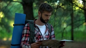 Confused camper orienteering with map in forest, searching for right way stock photo Confused camper orienteering with map in forest, searching for right way stock photo
