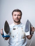 Confused man in burned shirt with two irons stock photo Confused man in burned shirt with two irons stock photo