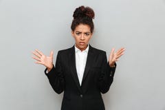 Confused young african business woman standing over grey wall stock photos Confused young african business woman standing over grey wall stock photos