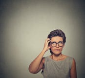 Confused думая женщина в стеклах сбивать царапать ее голову стоковая фотография Confused думая женщина в стеклах сбивать царапать ее голову стоковая фотография