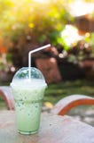Congele o chá verde no copo plástico na tabela foto de stock Congele o chá verde no copo plástico na tabela foto de stock