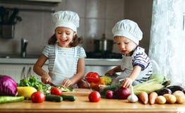 Consommation saine Les enfants heureux prépare la salade végétale dans le kitc photos stock Consommation saine Les enfants heureux prépare la salade végétale dans le kitc photos stock