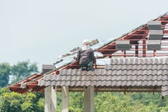 Construction roofer installing roof tiles at building site stock photos Construction roofer installing roof tiles at building site stock photos