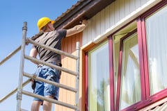 Construction worker on scaffolding painting wooden house facade royalty free stock image Construction worker on scaffolding painting wooden house facade royalty free stock image