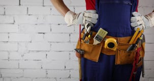 Construction worker with tool belt standing on white brick wall background