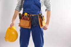 Construction Worker With Hard Hat And Tool Belt On Light Background. Space For Text Royalty Free Stock Photos