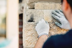 Constructionworker instaluje kamiennej ściany powierzchnię z cementem dla domowy odnawić obrazy royalty free Constructionworker instaluje kamiennej ściany powierzchnię z cementem dla domowy odnawić obrazy royalty free