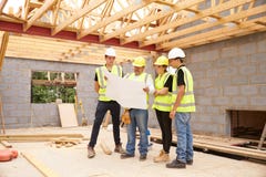 Constructor On Building Site que mira planes con los aprendices imagenes de archivo Constructor On Building Site que mira planes con los aprendices imagenes de archivo