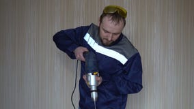Construtor considerável no uniforme com broca da terra arrendada da correia da ferramenta Homem novo farpado que trabalha com bro filme Construtor considerável no uniforme com broca da terra arrendada da correia da ferramenta Homem novo farpado que trabalha com bro filme