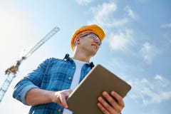 Construtor no capacete de segurança com o PC da tabuleta na construção fotografia de stock royalty free Construtor no capacete de segurança com o PC da tabuleta na construção fotografia de stock royalty free