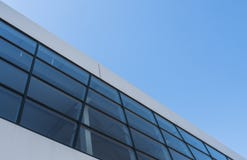 Construção com a fachada de alumínio branca com janelas e painéis do alumínio contra o céu azul fotografia de stock Construção com a fachada de alumínio branca com janelas e painéis do alumínio contra o céu azul fotografia de stock