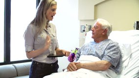 Consultant Talks To Senior Male Patient In Hospital Room