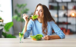 Consumición sana chica joven feliz que come la ensalada por mañana en cocina imágenes de archivo libres de regalías Consumición sana chica joven feliz que come la ensalada por mañana en cocina imágenes de archivo libres de regalías