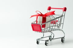 Contenitore di regalo bianco legato con il nastro rosso in un carrello immagini stock Contenitore di regalo bianco legato con il nastro rosso in un carrello immagini stock