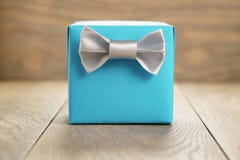 Contenitore di regalo blu-chiaro con l'arco d'argento minimalistic del nastro su di legno Immagini Stock Contenitore di regalo blu-chiaro con l'arco d'argento minimalistic del nastro su di legno Immagini Stock