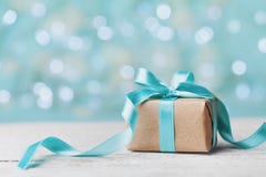 Contenitore di regalo di Natale contro il fondo del bokeh del turchese Cartolina d'auguri di festa fotografia stock libera da diritti Contenitore di regalo di Natale contro il fondo del bokeh del turchese Cartolina d'auguri di festa fotografia stock libera da diritti