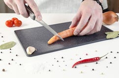 Cook cuts carrot on black cutting board stock image Cook cuts carrot on black cutting board stock image