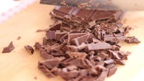 Cook wręcza tnącego czekoladowego baru z kuchennym nożem na tnącej desce obraz stock Cook wręcza tnącego czekoladowego baru z kuchennym nożem na tnącej desce obraz stock