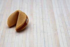 Cookie de fortuna chinesa em uma esteira de bambu fotografia de stock Cookie de fortuna chinesa em uma esteira de bambu fotografia de stock