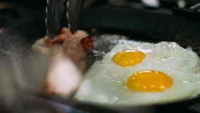 Cooking Delicious Fried Eggs with Bacon in Pan.