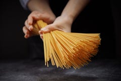 Hand made spaghetti in female hands against a dark background stock image Hand made spaghetti in female hands against a dark background stock image