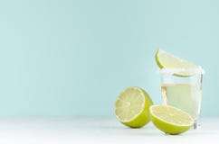 Cooking of summer fresh alcohol shot of tequila with lime, salt on rim on soft light pastel green background and white wood table. royalty free stock photo Cooking of summer fresh alcohol shot of tequila with lime, salt on rim on soft light pastel green background and white wood table. royalty free stock photo