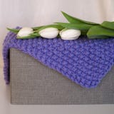 Coperta tricottata piegata sulla scatola grigia fotografia stock Coperta tricottata piegata sulla scatola grigia fotografia stock