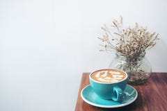 Copiez l'image de l'espace d'une tasse bleue de café chaud de latte et de fleurs sèches dans un vase sur la table en bois de vint images stock Copiez l'image de l'espace d'une tasse bleue de café chaud de latte et de fleurs sèches dans un vase sur la table en bois de vint images stock