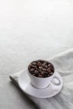 Copo de café enchido com os feijões de café imagem de stock Copo de café enchido com os feijões de café imagem de stock