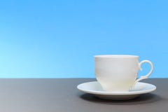 Copo de chá branco da porcelana do vintage na placa cinzenta e no fundo azul imagens de stock Copo de chá branco da porcelana do vintage na placa cinzenta e no fundo azul imagens de stock