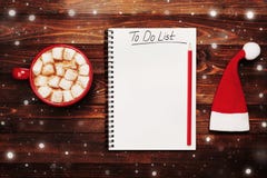 Copo do cacau ou do chocolate quente com o marshmallow, o chapéu de Santa e o caderno com para fazer a lista na tabela de cima de fotografia de stock royalty free Copo do cacau ou do chocolate quente com o marshmallow, o chapéu de Santa e o caderno com para fazer a lista na tabela de cima de fotografia de stock royalty free