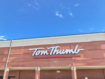 Logo at entrance of Tom Thumb grocery store under cloud blue sky