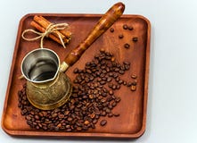 Copper coffee pot with coffee beans and cinnamon sticks. On a wooden plate board. Light background royalty free stock image Copper coffee pot with coffee beans and cinnamon sticks. On a wooden plate board. Light background royalty free stock image